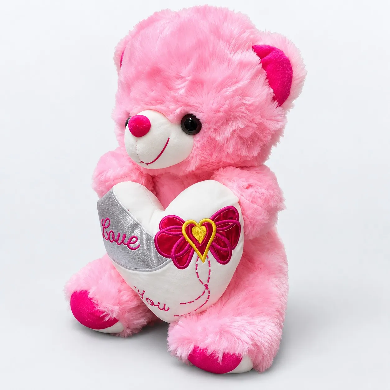 Fluffy pink teddy bear with a heart, side view